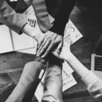 Ubezpieczenia grupowe dla firm - widok złączonych dłoni pracowników.