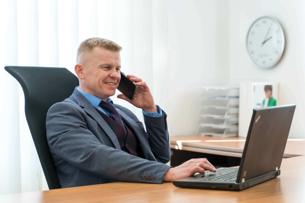 Agent ubezpieczeniowy z Tarnowa uśmiecha się rozmawiając z klientem przez telefon.